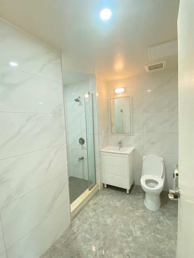 bathroom with tile walls, vanity, a shower with door, and toilet