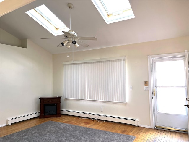 interior space with baseboard heating, ceiling fan, wood-type flooring, and lofted ceiling with skylight