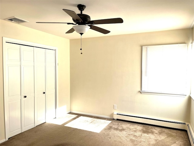 unfurnished bedroom with light carpet, a baseboard heating unit, a closet, and ceiling fan