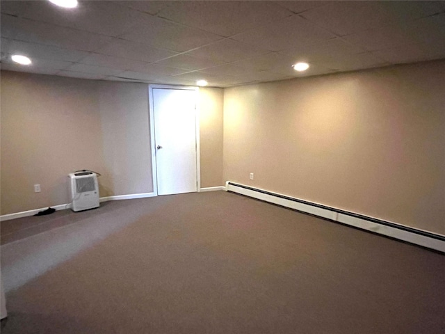 basement featuring a drop ceiling, a baseboard heating unit, and carpet floors