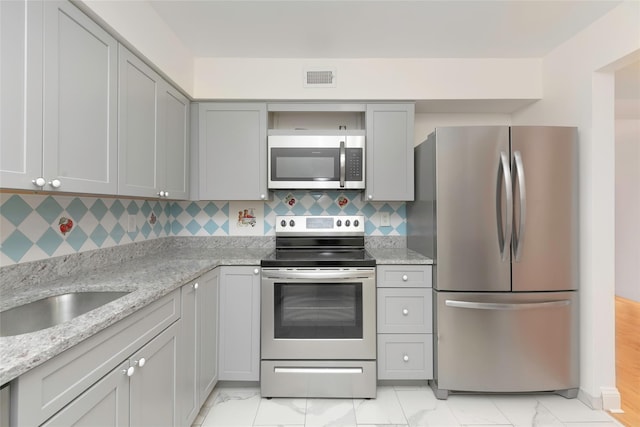 kitchen featuring sink, tasteful backsplash, appliances with stainless steel finishes, gray cabinets, and light stone countertops