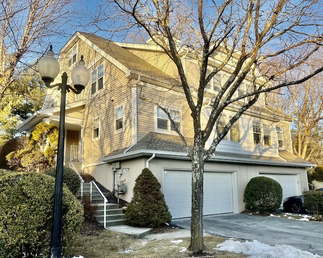 view of home's exterior with an attached garage, a shingled roof, and aphalt driveway