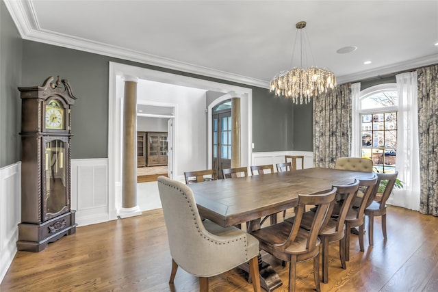 dining space with a notable chandelier, crown molding, dark wood-type flooring, and ornate columns