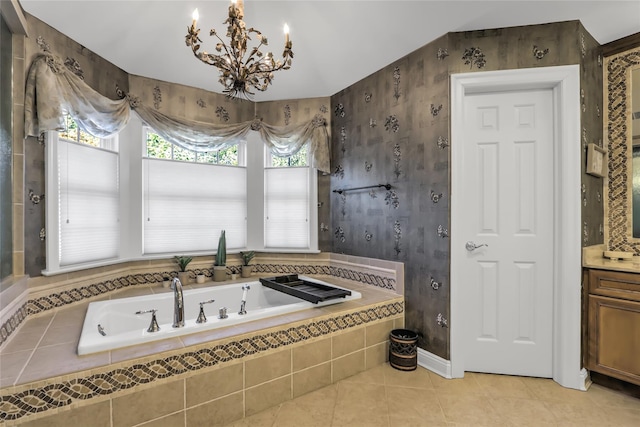 bathroom with an inviting chandelier, tile patterned floors, vanity, and tiled tub