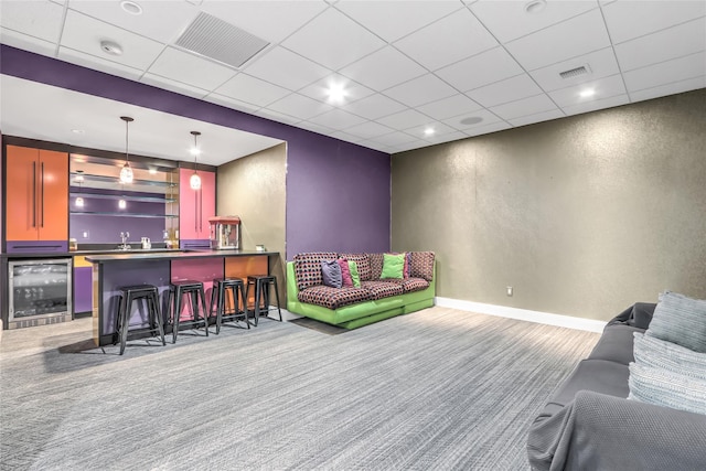 carpeted living room featuring a paneled ceiling, bar, and beverage cooler