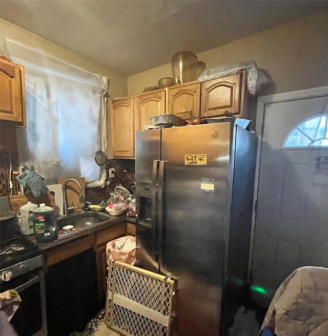 kitchen with stainless steel refrigerator with ice dispenser, oven, and sink