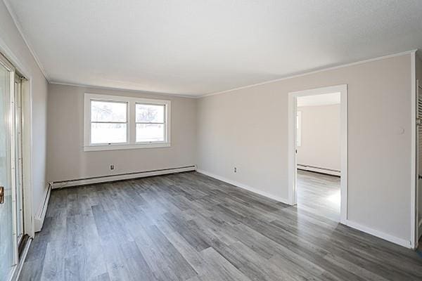 unfurnished room with ornamental molding, dark wood-style flooring, and baseboard heating