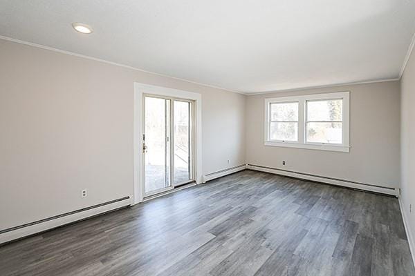 spare room featuring dark wood-type flooring, a baseboard radiator, and crown molding