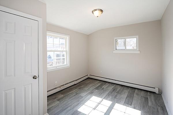 spare room featuring baseboards, baseboard heating, and wood finished floors