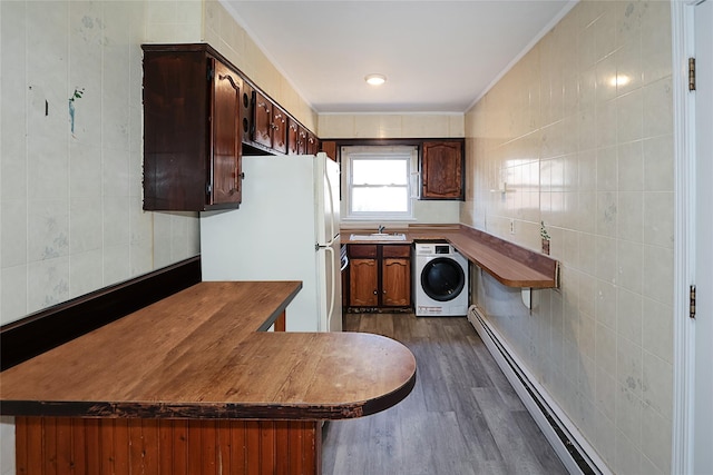 kitchen with washer / dryer, tile walls, freestanding refrigerator, a peninsula, and a sink