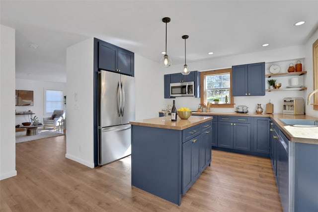 kitchen featuring sink, wooden counters, a center island, stainless steel appliances, and blue cabinetry