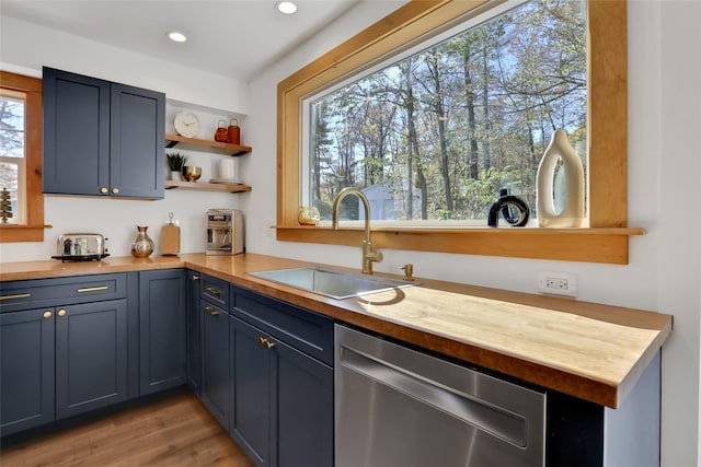 kitchen featuring blue cabinets, sink, wooden counters, light wood-type flooring, and dishwasher