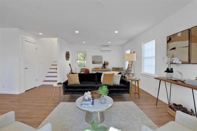 living room featuring plenty of natural light, a wall mounted AC, and light wood-type flooring