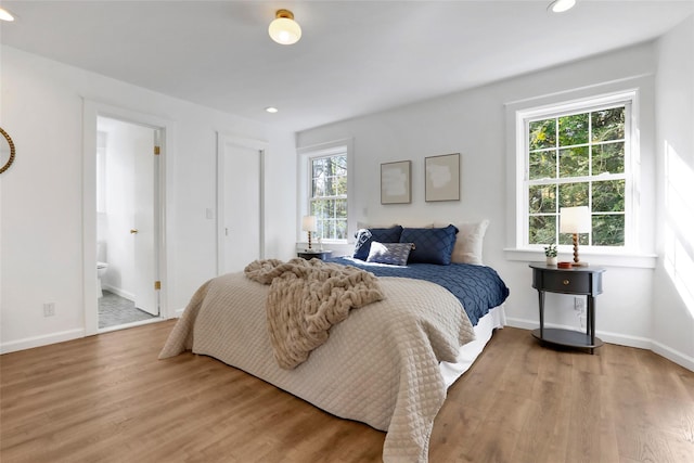 bedroom with hardwood / wood-style flooring and ensuite bath