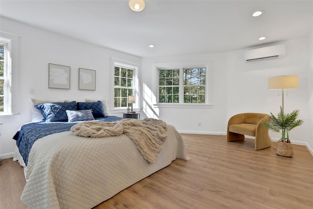 bedroom featuring a wall unit AC and light hardwood / wood-style floors