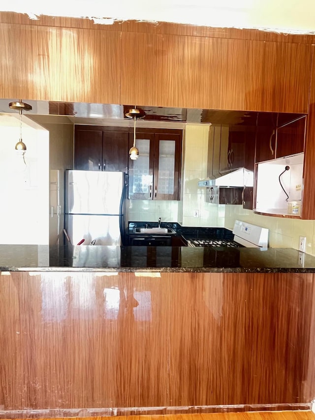 kitchen with tasteful backsplash, decorative light fixtures, stainless steel refrigerator, and white stove