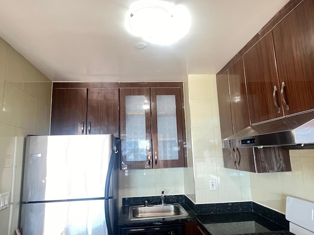 kitchen with stainless steel fridge, sink, tile walls, and backsplash