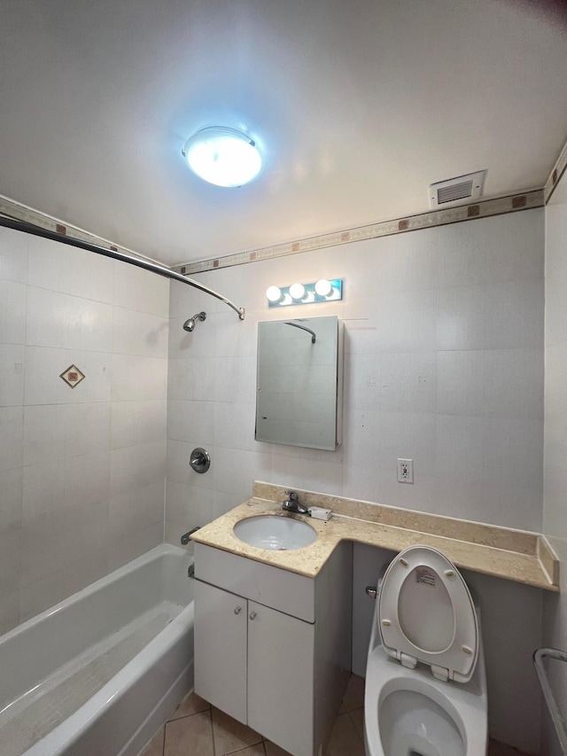 full bathroom featuring tiled shower / bath, tile walls, vanity, toilet, and tile patterned floors