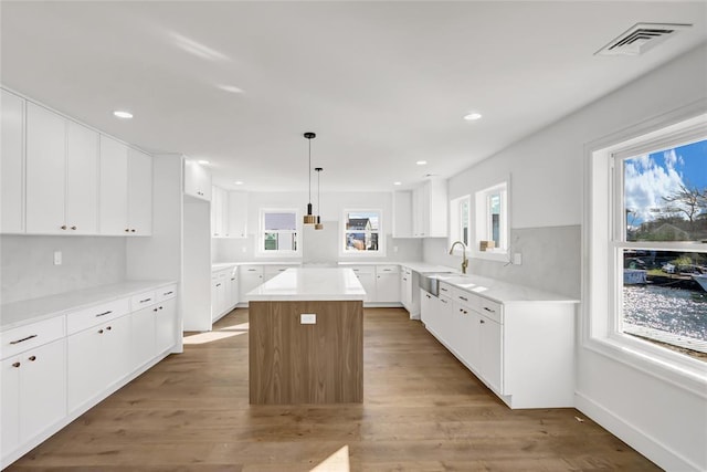 kitchen with white cabinetry, a center island, hardwood / wood-style floors, and pendant lighting