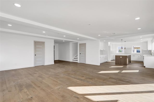 unfurnished living room with dark wood-type flooring, sink, and beam ceiling