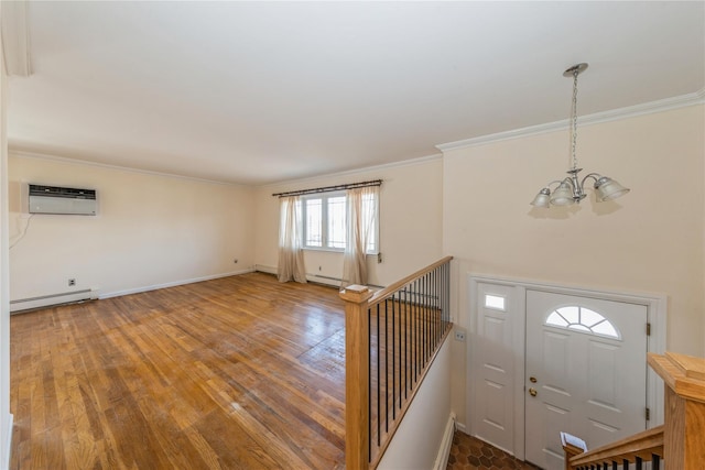 foyer entrance featuring hardwood / wood-style flooring, crown molding, a baseboard heating unit, and an inviting chandelier