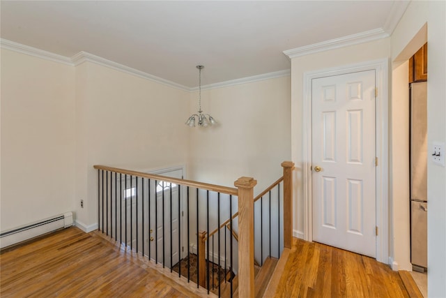 stairs featuring crown molding, hardwood / wood-style floors, a notable chandelier, and baseboard heating