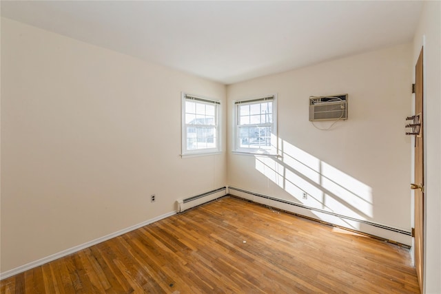 empty room with wood-type flooring, a wall unit AC, and a baseboard heating unit