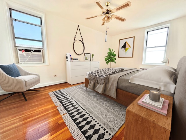 bedroom with light wood-style floors, baseboards, and cooling unit