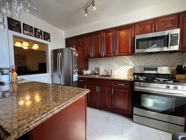 kitchen featuring stainless steel appliances, a sink, marble finish floor, decorative backsplash, and dark stone countertops