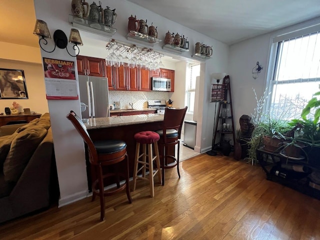 kitchen featuring appliances with stainless steel finishes, a breakfast bar, a wealth of natural light, and light wood-style floors