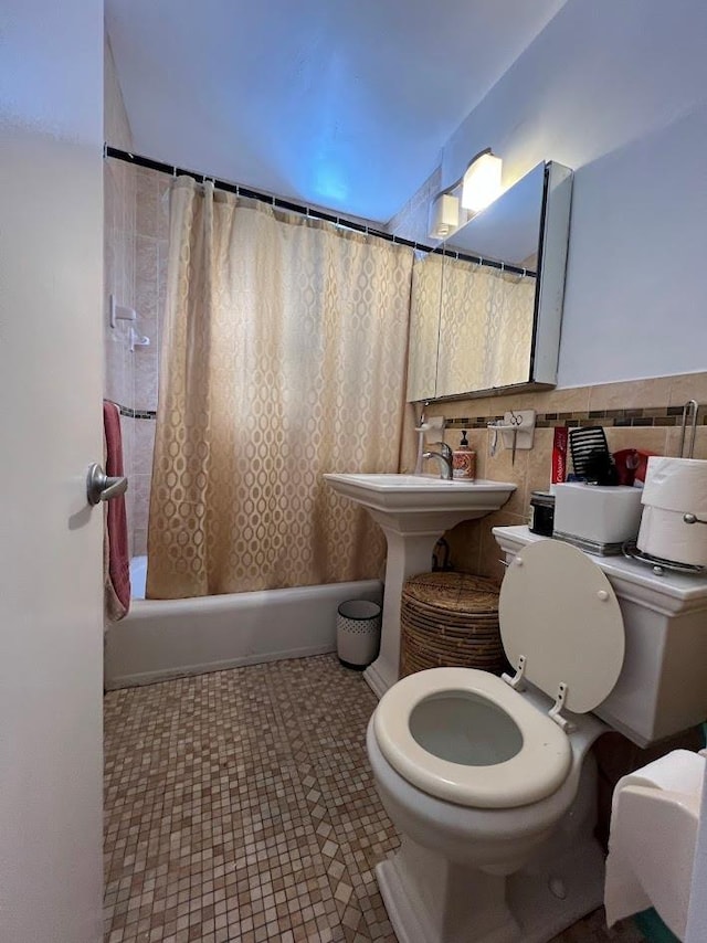 full bathroom with a sink, shower / tub combo with curtain, tile walls, and toilet