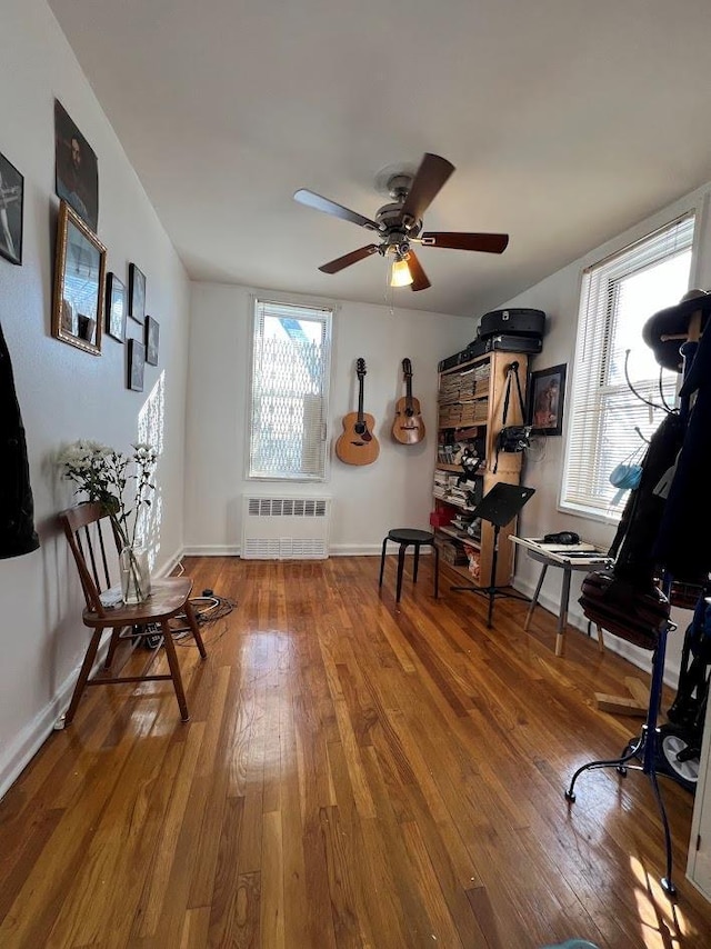 sitting room featuring baseboards, ceiling fan, wood-type flooring, and radiator