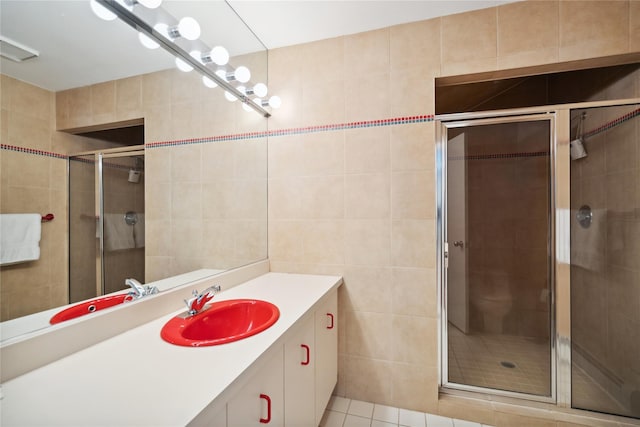 bathroom with tile walls, vanity, tile patterned flooring, and a shower with shower door