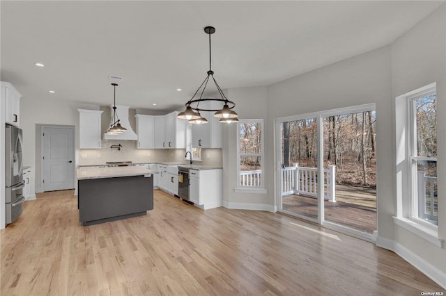 kitchen with backsplash, stainless steel appliances, white cabinets, a kitchen island, and decorative light fixtures