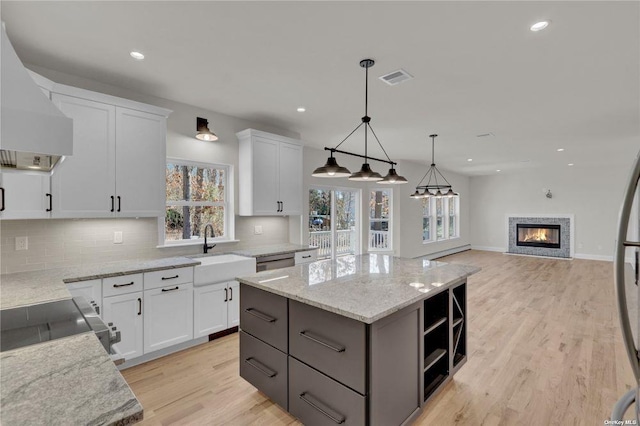 kitchen featuring pendant lighting, sink, white cabinets, a kitchen island, and custom exhaust hood