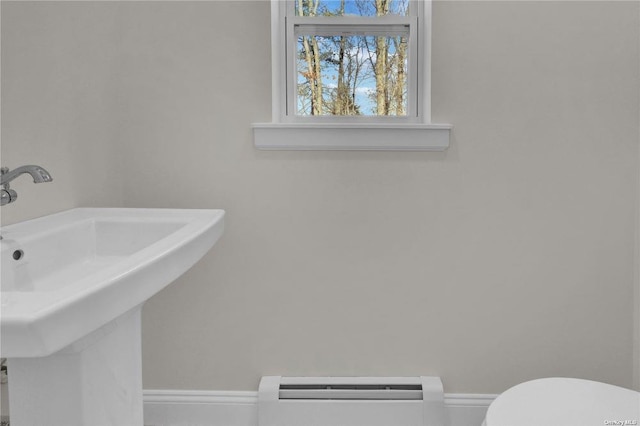 bathroom featuring toilet, sink, and a baseboard heating unit