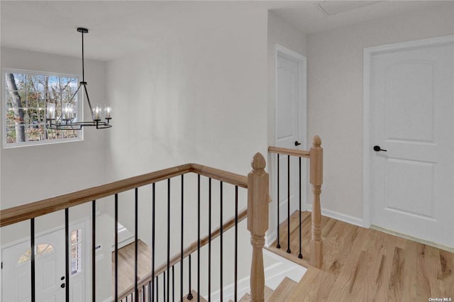 stairs featuring hardwood / wood-style floors and a notable chandelier