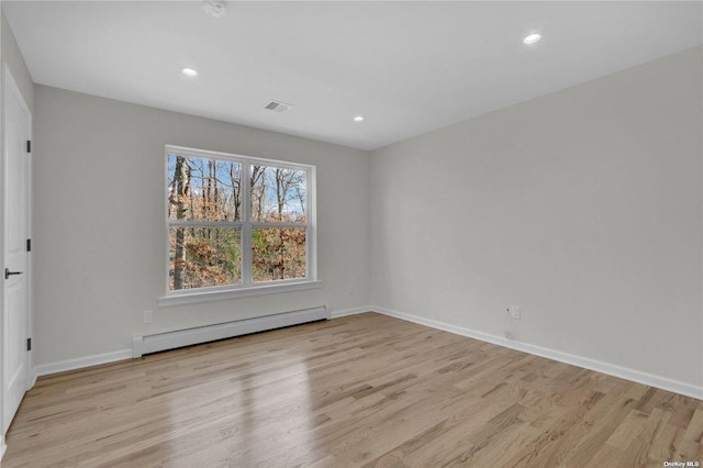 spare room with baseboard heating and light hardwood / wood-style flooring