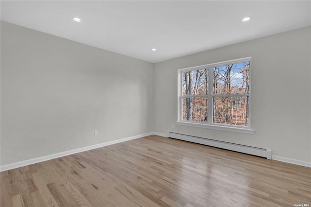 spare room with a baseboard radiator and light wood-type flooring