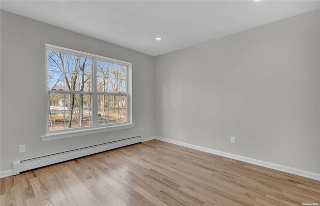 spare room with baseboard heating and light wood-type flooring