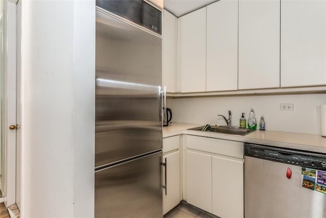 kitchen with appliances with stainless steel finishes, white cabinets, light countertops, and a sink