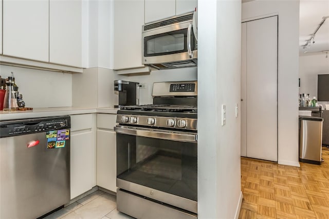 kitchen featuring rail lighting, white cabinetry, appliances with stainless steel finishes, and light countertops