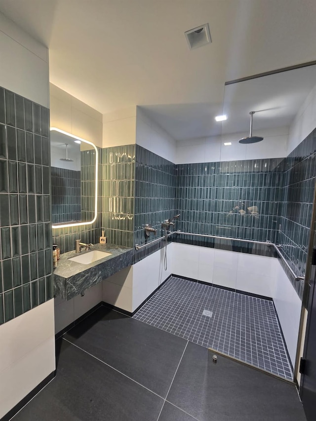 bathroom featuring tile walls, visible vents, a sink, tile patterned flooring, and walk in shower