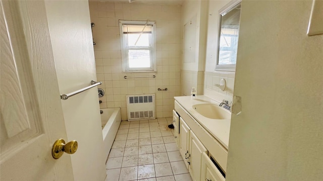 bathroom featuring a tub to relax in, tile walls, vanity, radiator, and tile patterned flooring