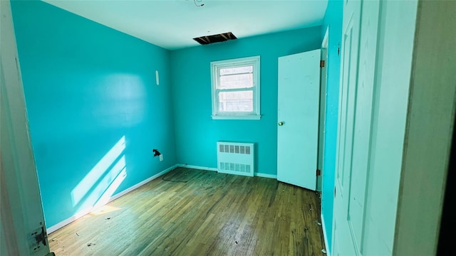 empty room with radiator and hardwood / wood-style floors