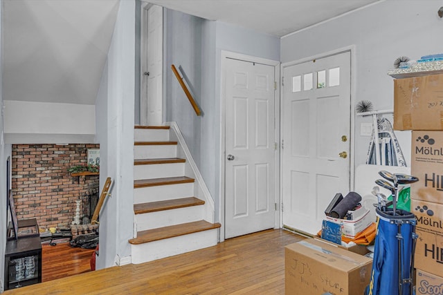 entrance foyer featuring brick wall, stairway, and light wood-style flooring