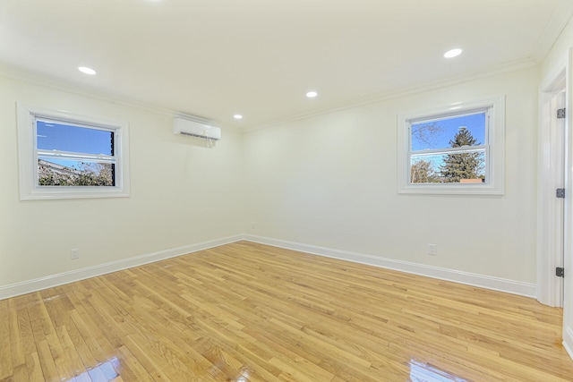 spare room featuring crown molding, light hardwood / wood-style flooring, a wall unit AC, and plenty of natural light