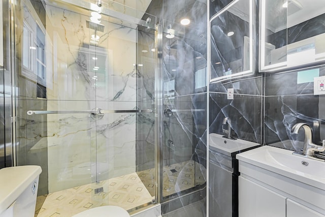 bathroom featuring a shower with shower door, tasteful backsplash, tile walls, vanity, and toilet