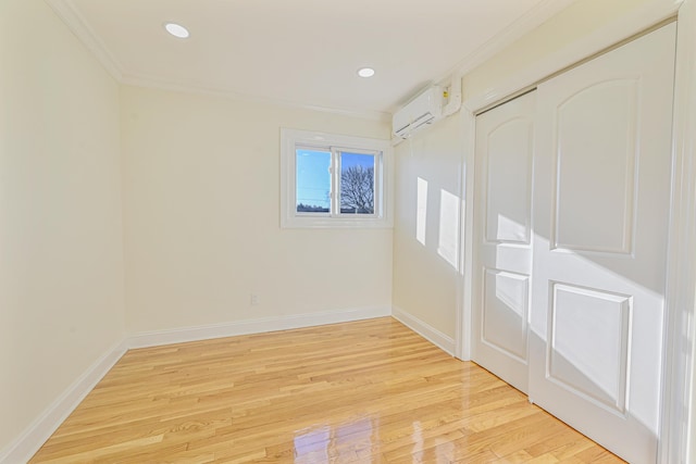 spare room with ornamental molding, a wall mounted air conditioner, and light hardwood / wood-style flooring