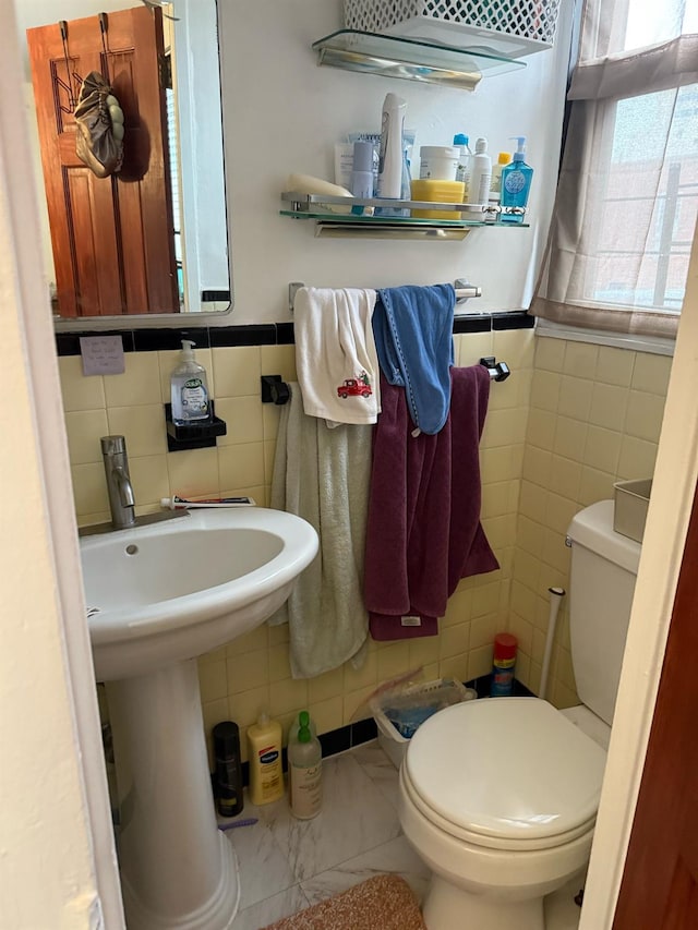 bathroom featuring wainscoting, tile walls, and toilet